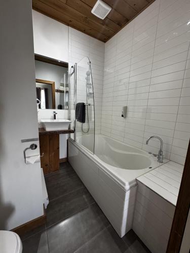 a white bathroom with a tub and a sink at Gîte du Haut des Arbres in Saguenay