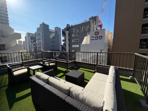 a balcony with a couch and tables and buildings at Plan A Tennozu Isle in Tokyo