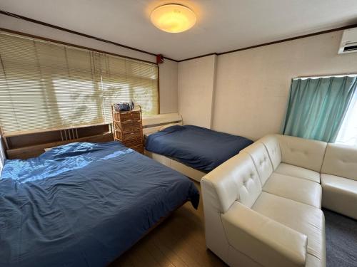 Private Retreat Nagasaki Vogelnest 2階貸切屋上テラス貸切長崎スタジアム5分 في ناغاساكي: غرفة معيشة بها سريرين وأريكة