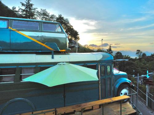 a blue van with an umbrella on top of it at Rooftop Converted School Bus in San Marcos La Laguna