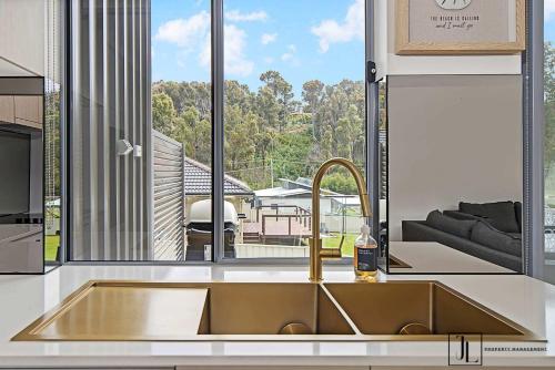 a kitchen with a sink and a large window at Bay Dream. in Malua Bay