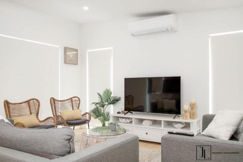 a living room with a couch and a tv at Bay Dream. in Malua Bay