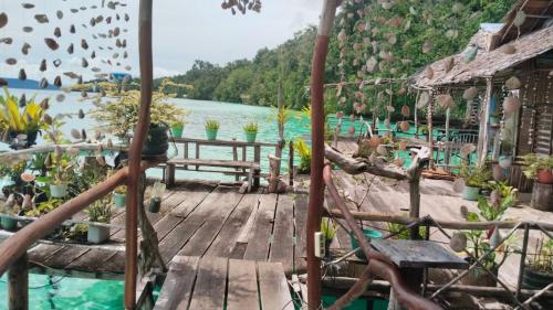 una terraza de madera con sillas y una masa de agua en Yenbainus homestay, en Yennanas Besir