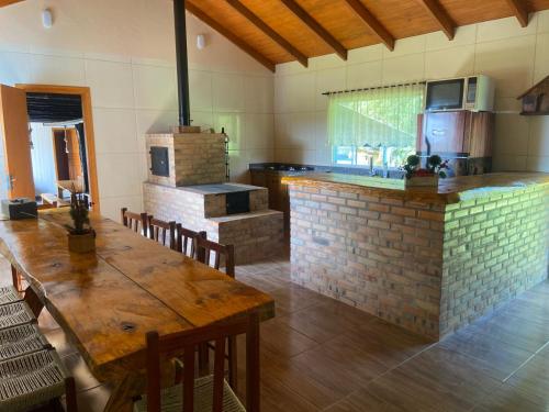 una cucina con tavolo in legno e un forno in mattoni di Chácara Leopoldo Bairro a Lages