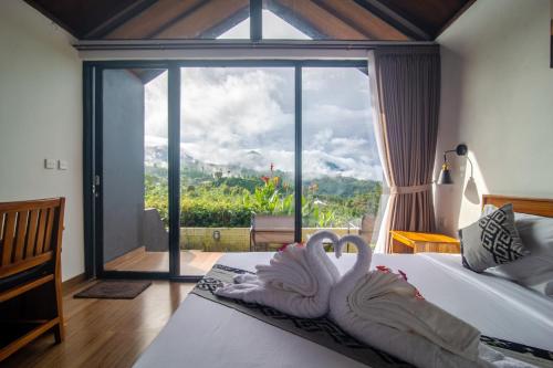 a bedroom with two swans on a bed with a large window at Alam Munduk Cabin in Munduk
