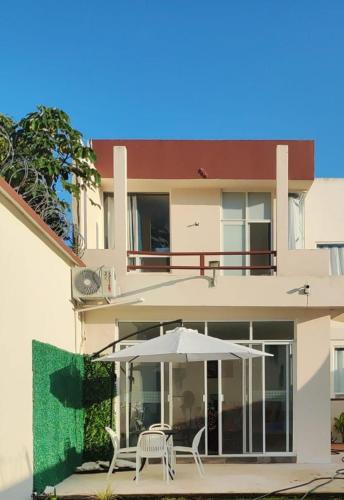 un bâtiment avec un parasol et deux chaises blanches dans l'établissement Villas Carlota Cancún, à Cancún