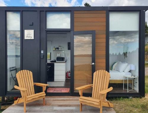 a tiny house with two chairs and a bed at Aorangi Peak Cabins 7 by Tiny Away in Rotorua