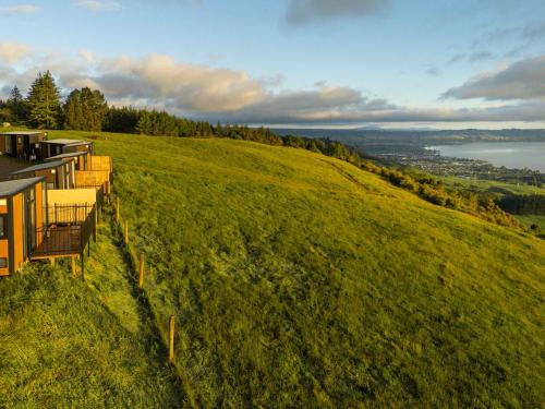 a house on a hill with a view of the water at Aorangi Peak Cabins 7 by Tiny Away in Rotorua