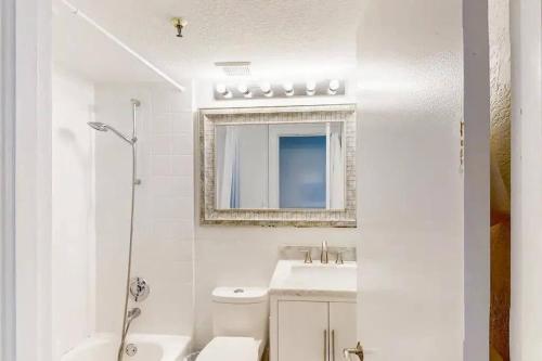 a white bathroom with a sink and a mirror at Palm Beach Condo 5 Mins to Beach Heated Pool in Palm Beach
