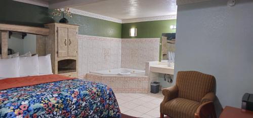 a bedroom with a bed and a tub and a chair at Sycamore Inn Chico University Area in Chico
