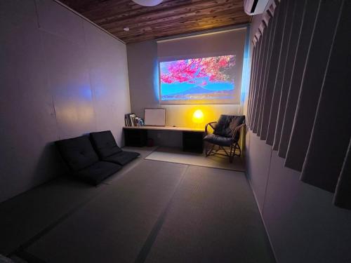 a living room with a large screen on the wall at houranoieホウラノイエ 四国香川高松 in Takamatsu