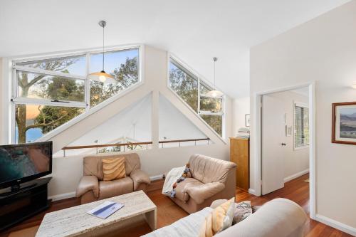 a living room with a large group of windows at Scotland Island Lodge in Scotland Island