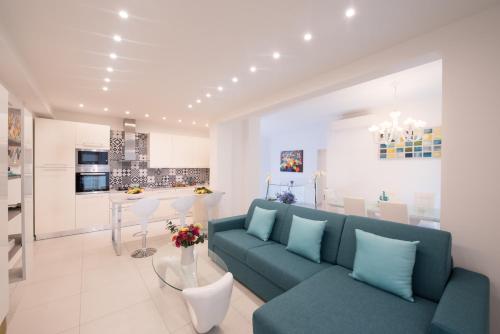 uma sala de estar com um sofá azul e uma cozinha em Al Corso Apartments by AMALFIVACATION em Minori