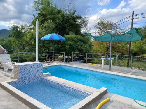 a pool with an umbrella and a chair at Aguaribay in Villa Los Aromos