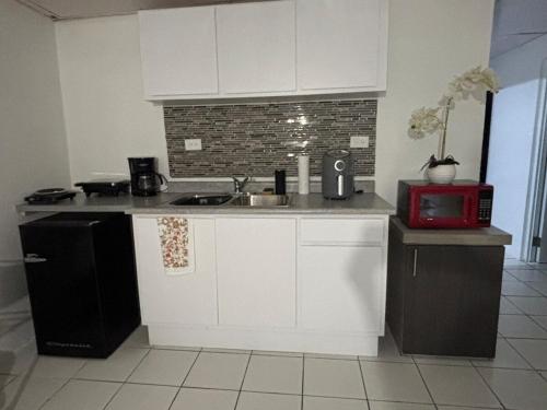 Una cocina con gabinetes blancos, un fregadero y un microondas. en Sweet Home, en San Juan