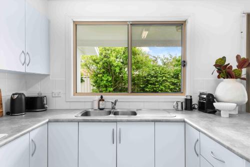 a white kitchen with a sink and a window at The Little Husky by Experience Jervis Bay in Huskisson