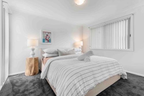 a white bedroom with a bed and two lamps at The Little Husky by Experience Jervis Bay in Huskisson