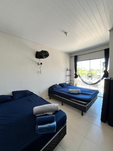 a bedroom with two beds and a window at Duplex em Itaúna 4min da Praia que ocorre o WSL, 1min da pista de skate do LS, pracinha com parque infantil, quadra de futebol, tudo isso a 1 min da duplex, perto do comércio, wi-fi super rápido, monitoramento 24hrs in Saquarema