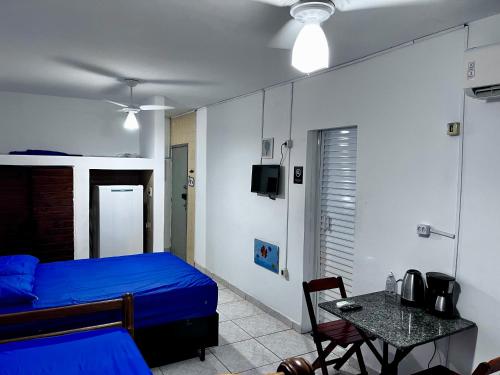 a bedroom with a blue bed and a table and a tableablish at Kit do ALEX - AVIAÇÃO - a uma esquina da praia - Ar Condicionado in Praia Grande