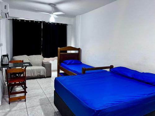 a bedroom with two beds and a chair and a couch at Kit do ALEX - AVIAÇÃO - a uma esquina da praia - Ar Condicionado in Praia Grande