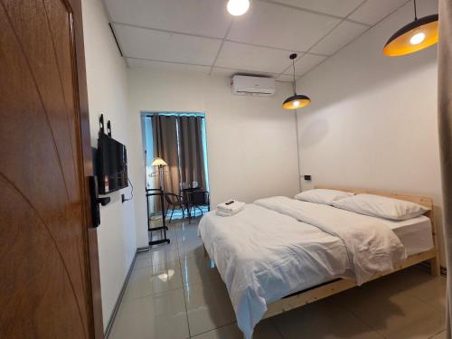 a bedroom with a bed and a flat screen tv at Nido Nomad Lodge in Tamparuli