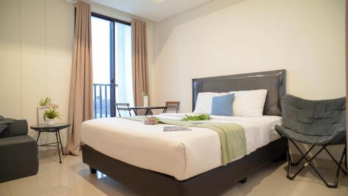 ジャカルタにあるSpacious and Homey Studio at Cleon Park Apartment By Travelioのベッドルーム(大型ベッド1台、椅子付)
