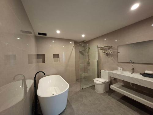 een badkamer met een bad, een toilet en een wastafel bij Velin Pattaya Hotel in Ban Nong Chaeng