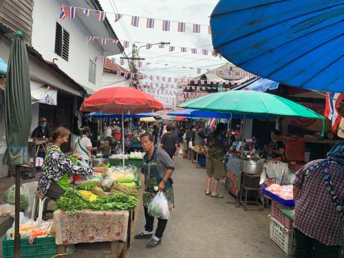 a group of people in an outdoor market with umbrellas at Home of River Kwai 2 in Kanchanaburi City