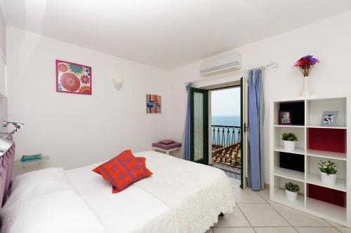 a white bedroom with a bed and a balcony at Fruit Flats by AMALFIVACATION in Minori