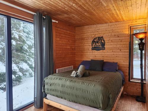 een slaapkamer met een bed in een blokhut bij Chalet Beausite in Saint-Philémon