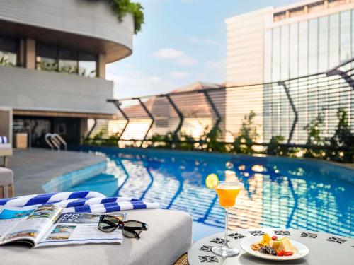 a table with a drink and a plate of food next to a pool at Novotel Goa Panjim in Panaji