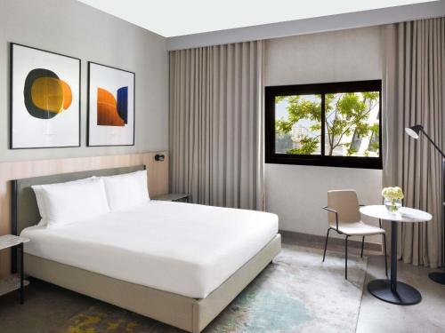 Un dormitorio con una cama blanca y una mesa. en Aparthotel Adagio Abidjan Marcory, en Abiyán