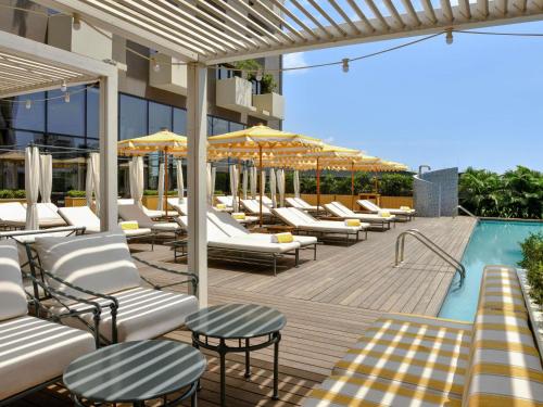 una piscina con tumbonas y sombrillas junto a un edificio en Aparthotel Adagio Abidjan Marcory, en Abiyán