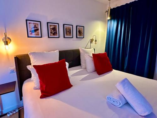 a bedroom with a bed with red and white pillows at Apt Place de Toscane - 4min Disneyland-PARIS in Serris