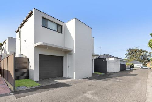 a white house with a garage on a street at Bonanza Lane Hideaway in Sydney
