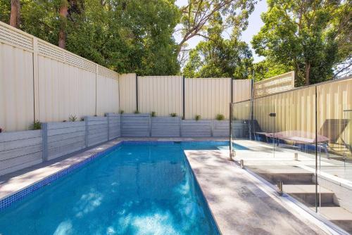 a swimming pool in a backyard with a fence at Bentley Beach Villa in Nelson Bay