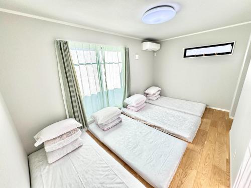 a room with three beds and a window at 海神ハウス in Funabashi