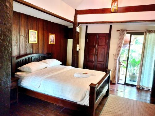 Sukjai Homestay في شيانغ ماي: غرفة نوم بسرير كبير مع جدار خشبي