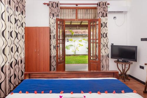 Una habitación con una cama y un televisor y una puerta. en Villa 95 - Private Villa in Ahungalla, en Ahungalla