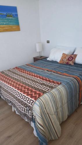 a bed with a colorful blanket on top of it at CostaQuilen Departamento in Puchuncaví