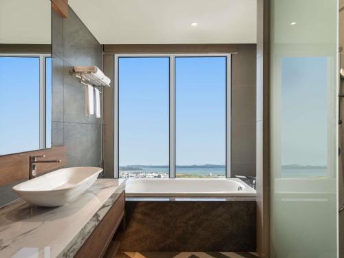 un baño con bañera y lavabo en Grand Mercure Batam Centre, en Batam Centre