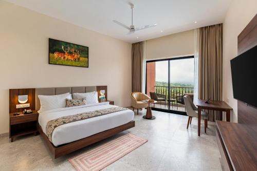 Osian Valley Resort & Spa Kumbhalgarh في Jāmb: غرفة نوم بها سرير ومكتب وتلفزيون