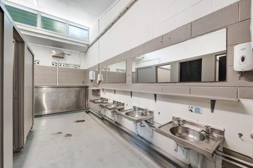 a public bathroom with three sinks and mirrors at Waitangi Holiday Park in Paihia