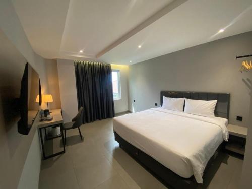 Un dormitorio con una cama blanca grande y un escritorio en MBS HOTEL Medan, en Medan