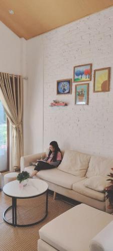 a woman sitting on a couch in a living room at Sunny House Homestay in Tam Ðảo