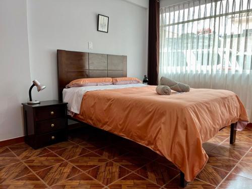 ein Schlafzimmer mit einem großen Bett mit einer orangefarbenen Tagesdecke in der Unterkunft Cozy & Centric Apartment in great location! in Cusco