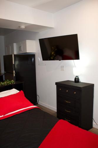 a bedroom with a black dresser and a flat screen tv at Studio - Cozy Downtown Hideaway in Sudbury