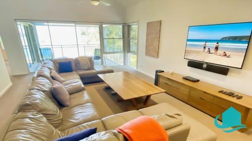 a living room with a couch and a flat screen tv at Pelican Escape Executive Home in Cams Wharf