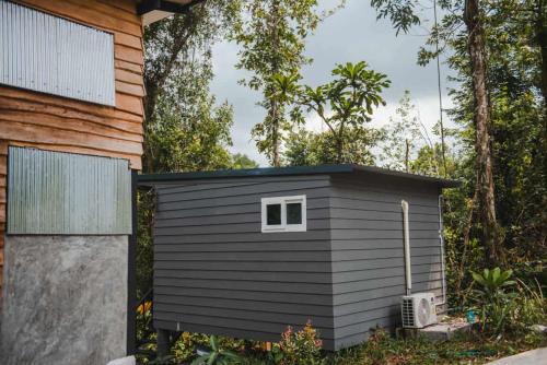 库德岛My Home Koh Kood1的房子旁边有个黑色的小棚子。