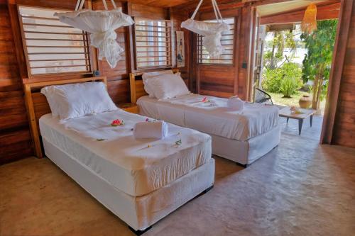 two beds sitting in a room with windows at Beach Villa l'Heure Bleue in Madirokely